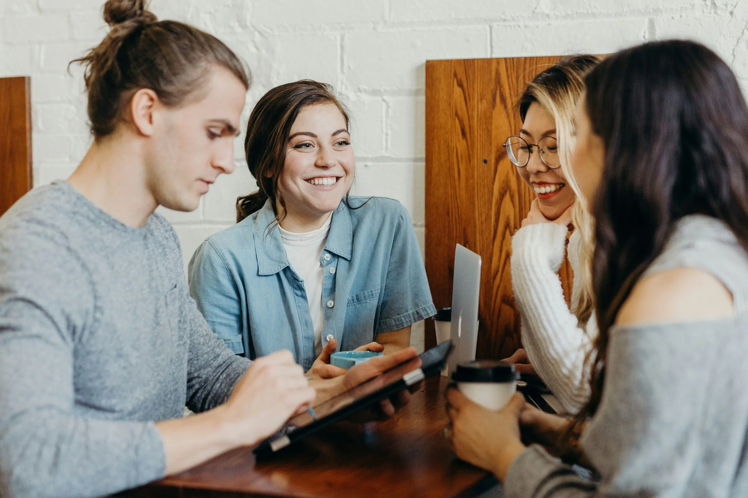 Four people sitting around a table, talking and smiling. (There is no text to transcribe.)